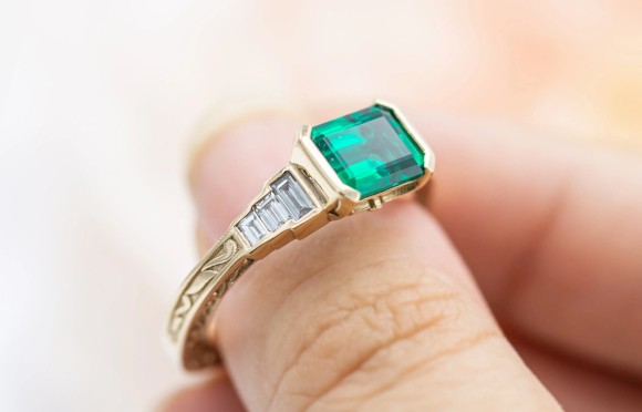 Emerald engagement ring on fingertip