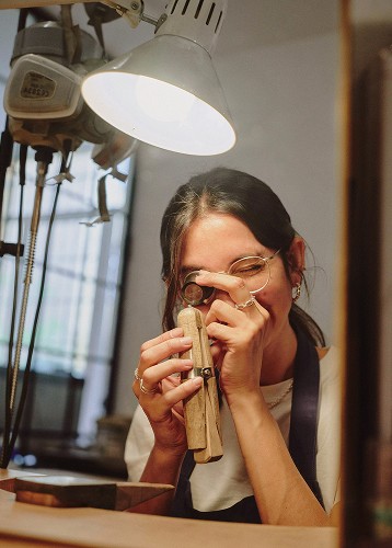 Woman inspecting gem with loupe