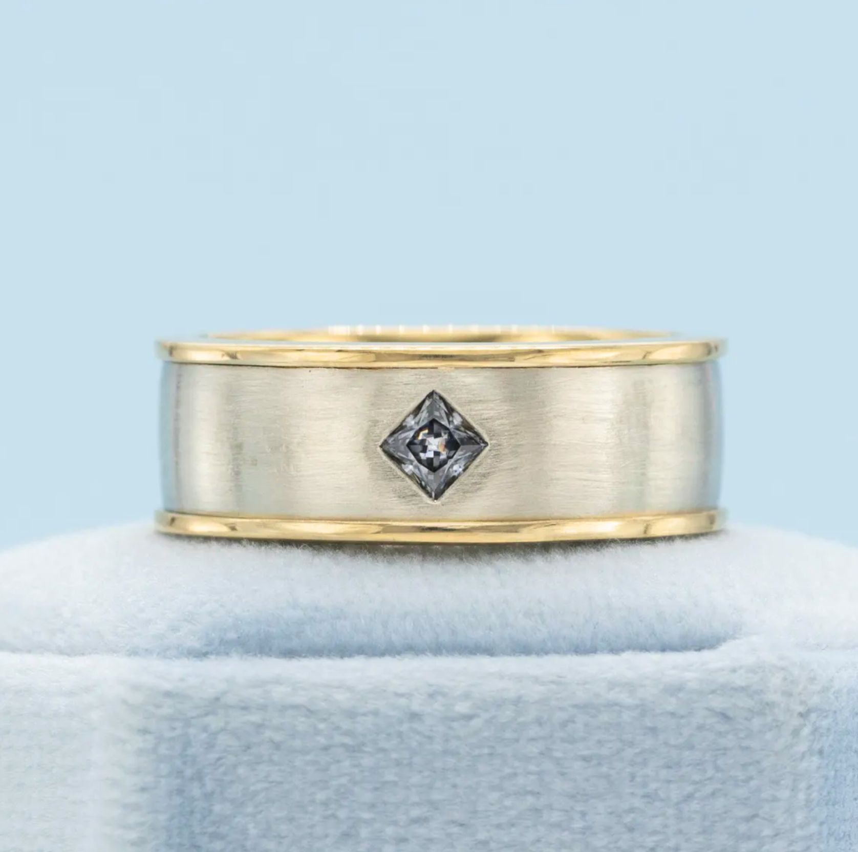 Mixed metal wedding band with a princess cut grey moissanite stone.
