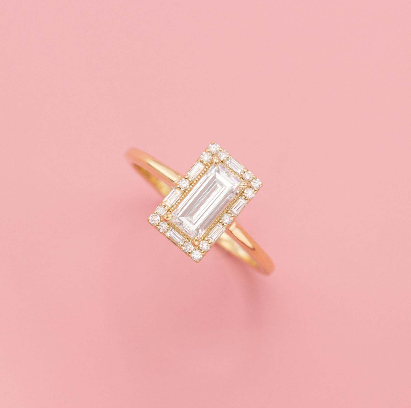 Dainty diamond engagement ring with a baguette diamond center stone and unique diamond halo.