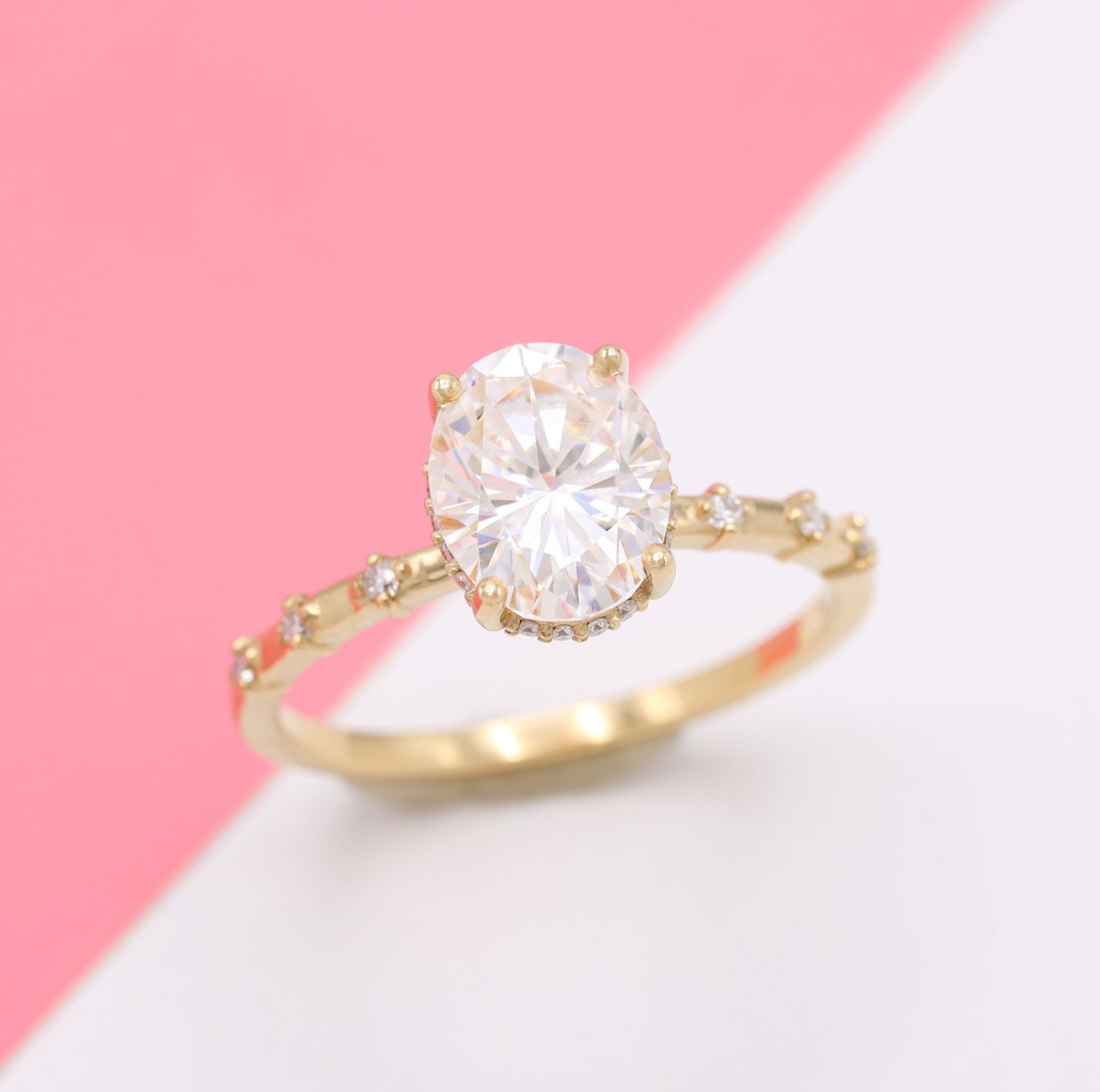 Oval moissanite engagement ring with dainty pavé band.