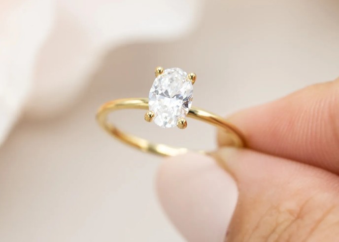 Slender diamond engagement ring held in hand